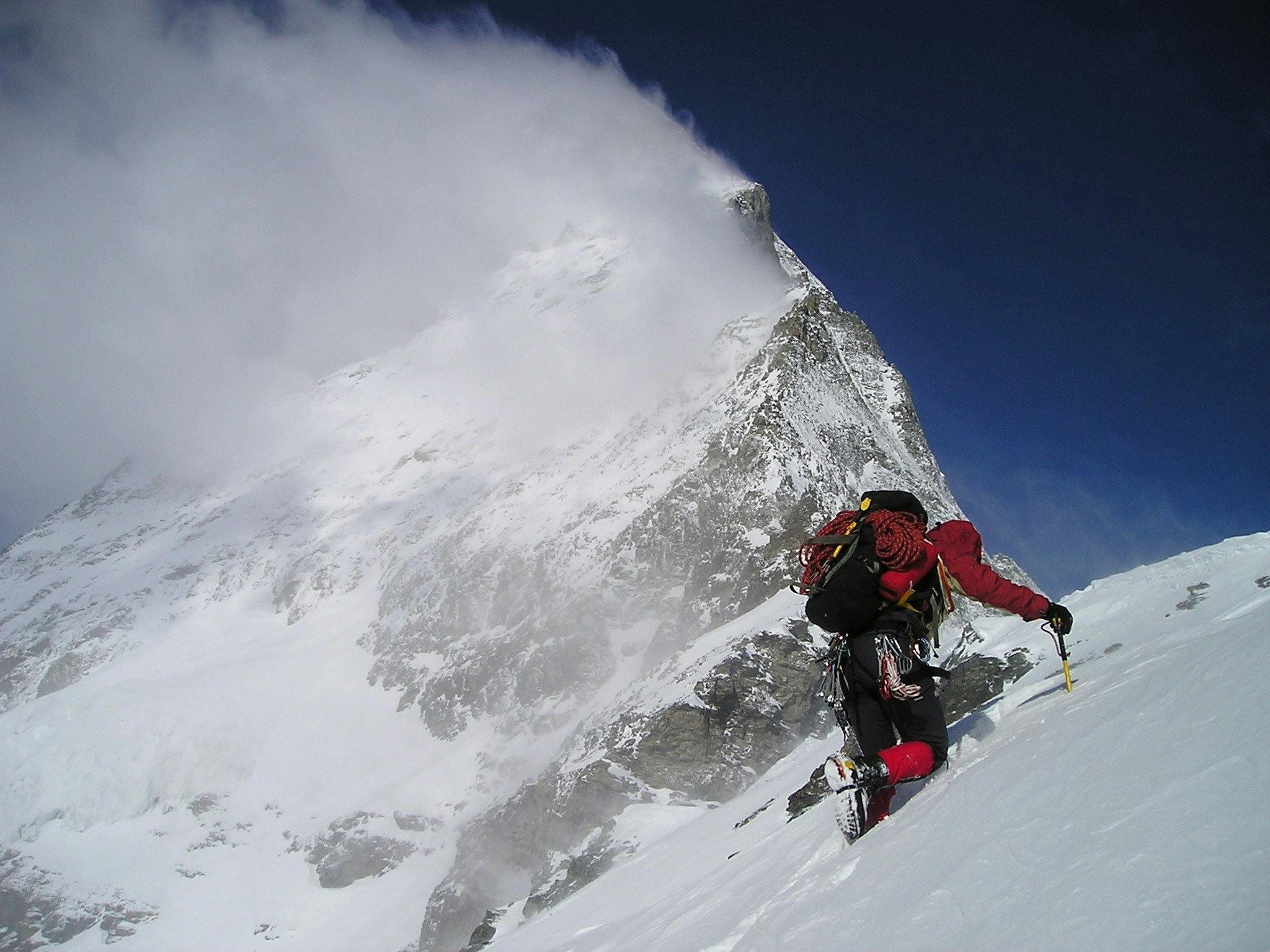 Climber celebrating atop a challenging summit, holding climbing hexes